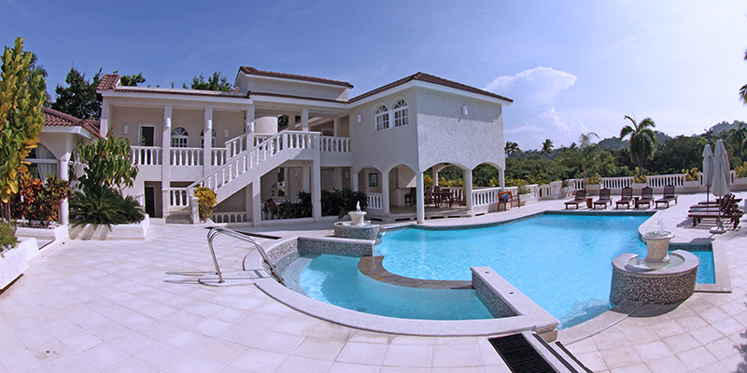 Large white house with a pool and surrounding garden