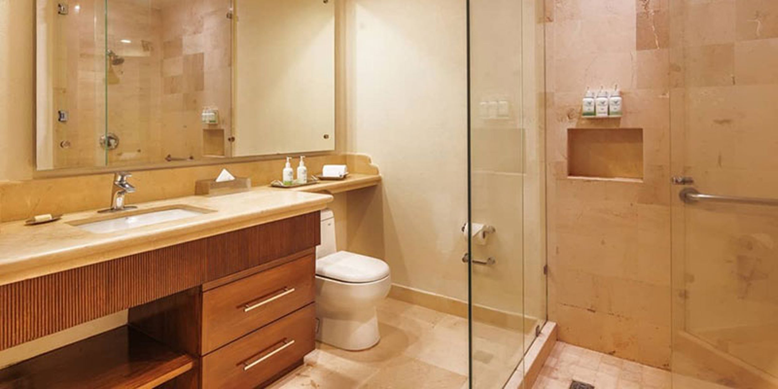 Bathroom with wooden vanity, toilet, and shower stall.