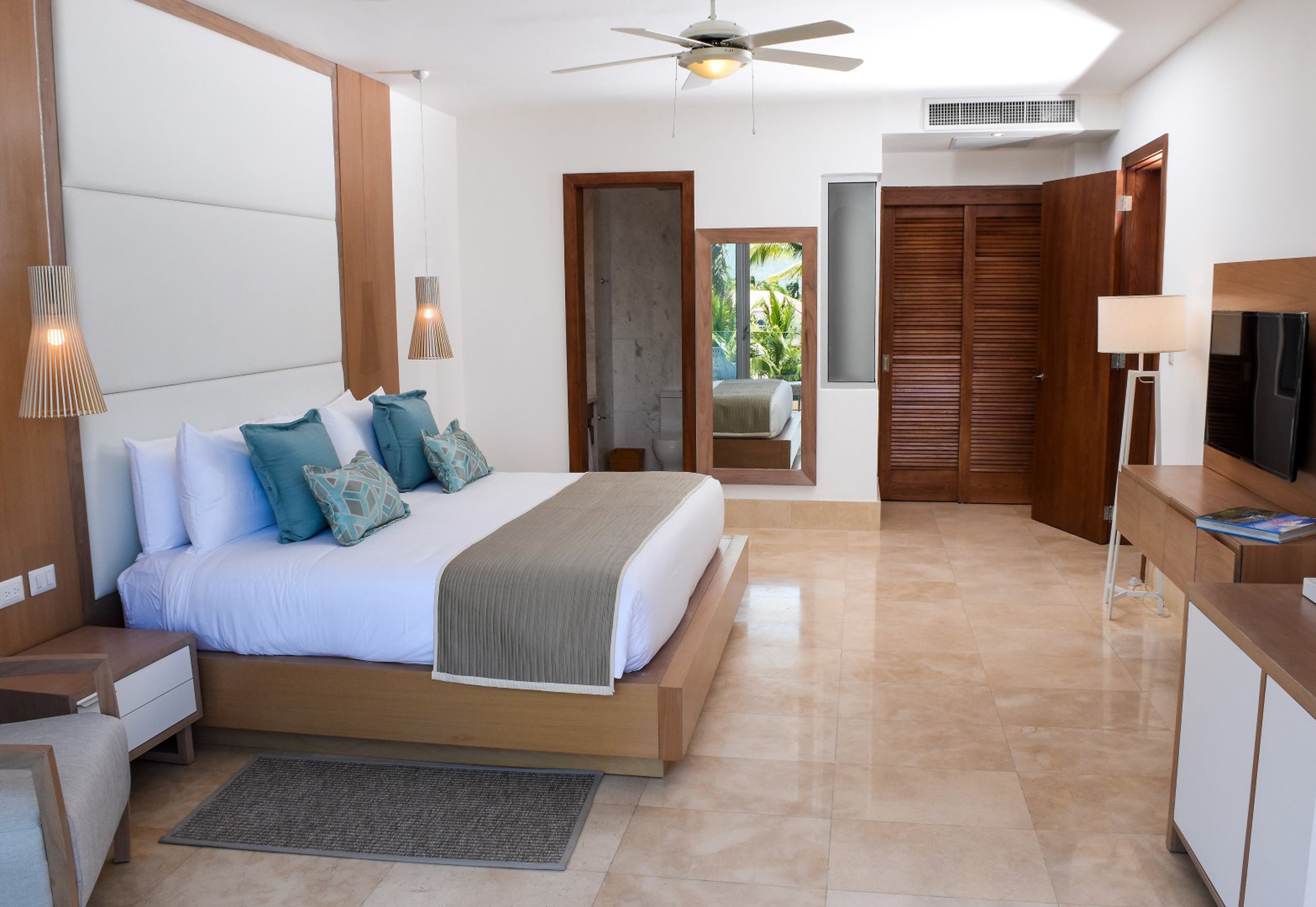 Modern bedroom with a large bed, wooden furniture, and a view of the outdoors.