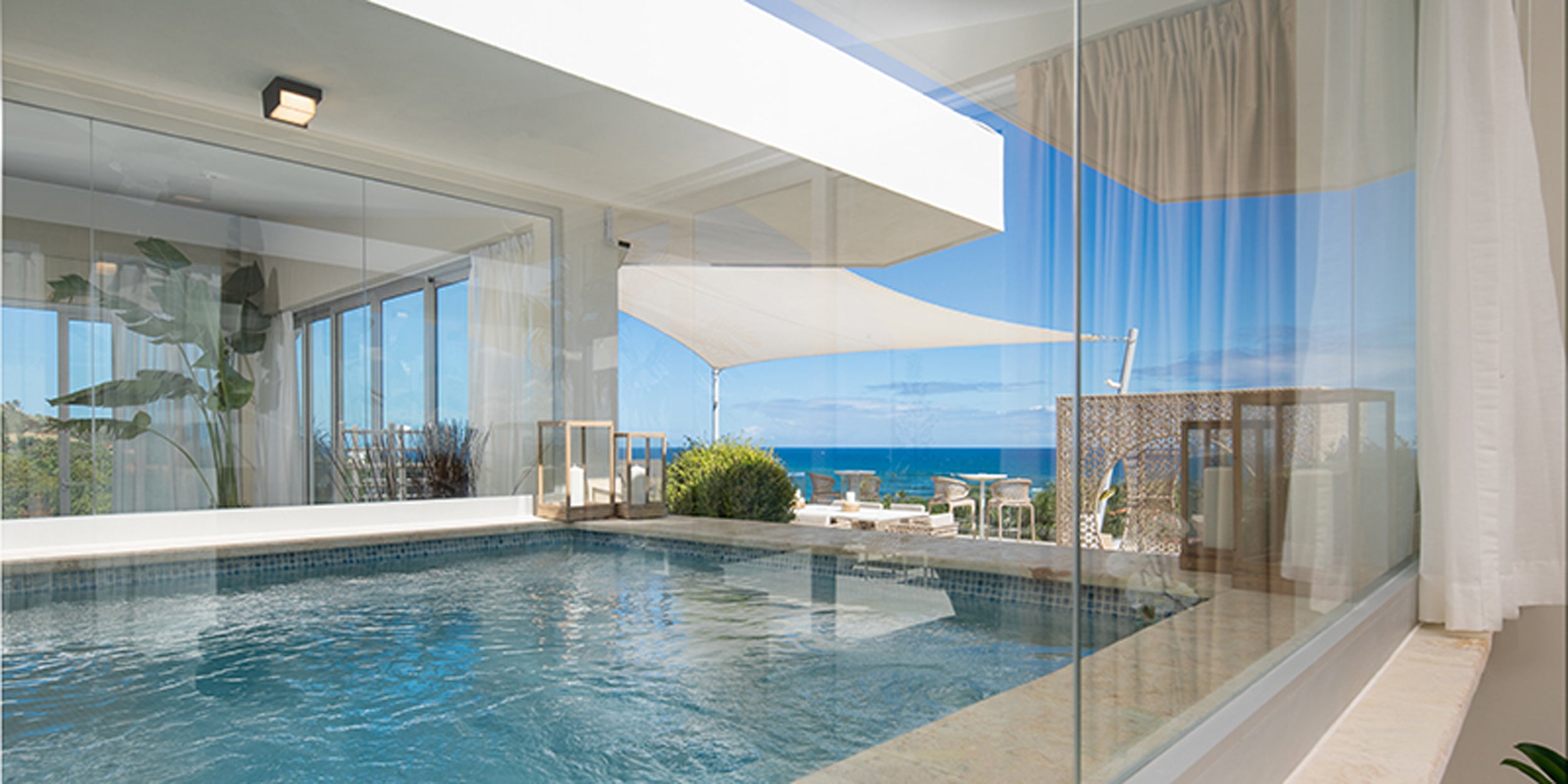 Modern indoor pool with large glass windows overlooking a scenic ocean view.