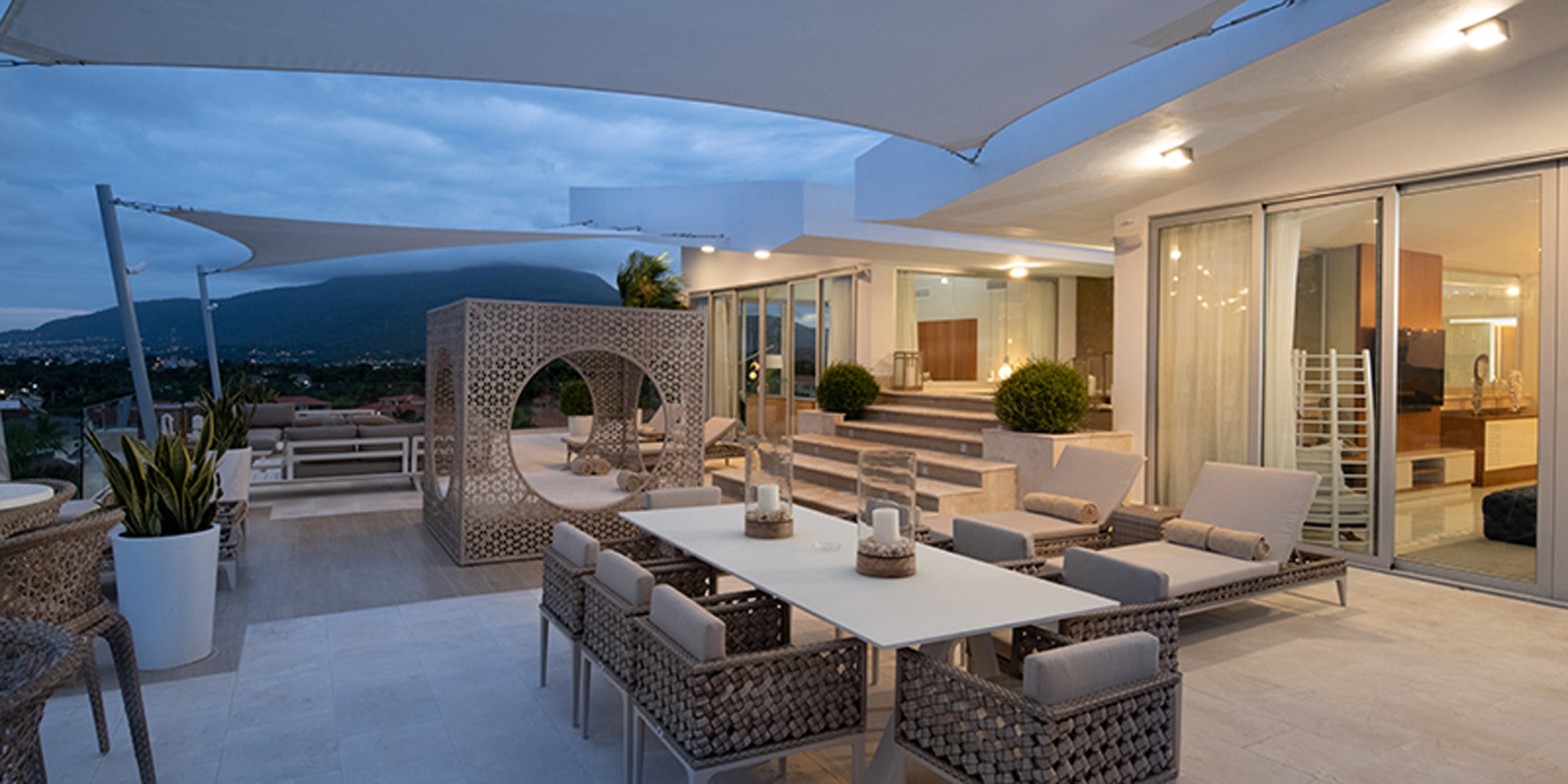 Modern outdoor patio with dining table, chairs, and umbrella at dusk.