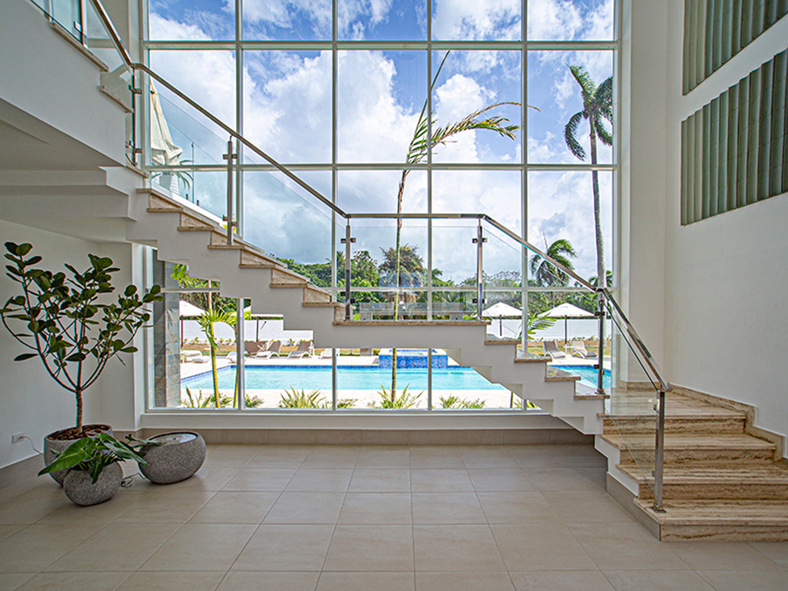Modern indoor staircase with large glass windows overlooking a pool and garden.