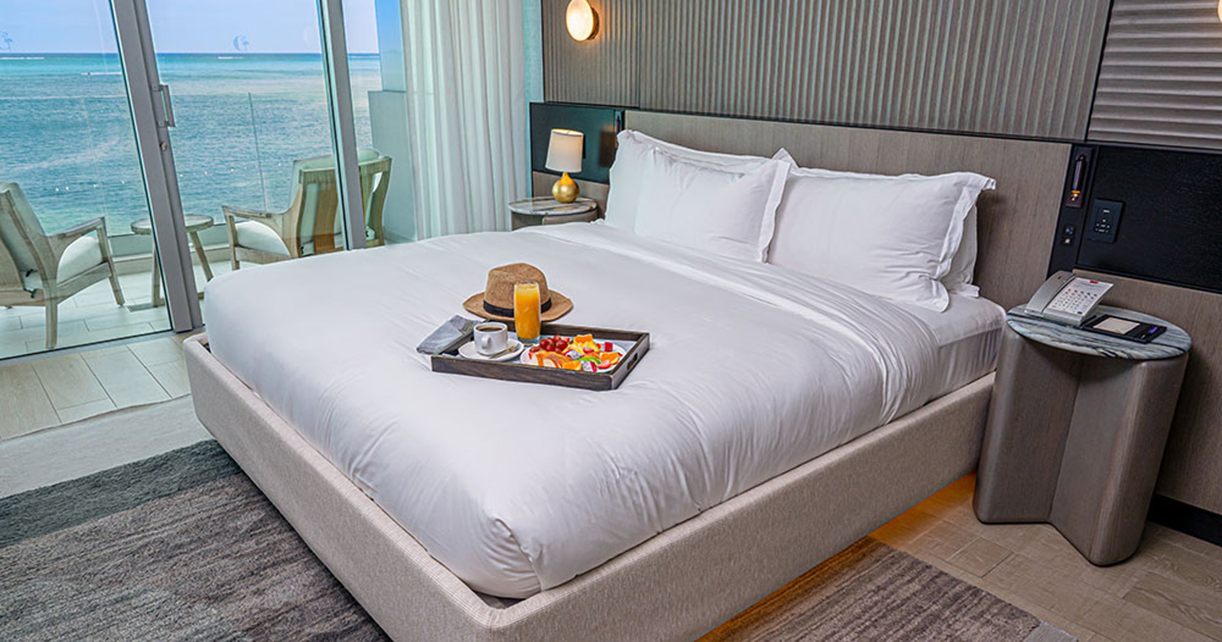 Bedroom with a bed, tray of fruit, and ocean view.