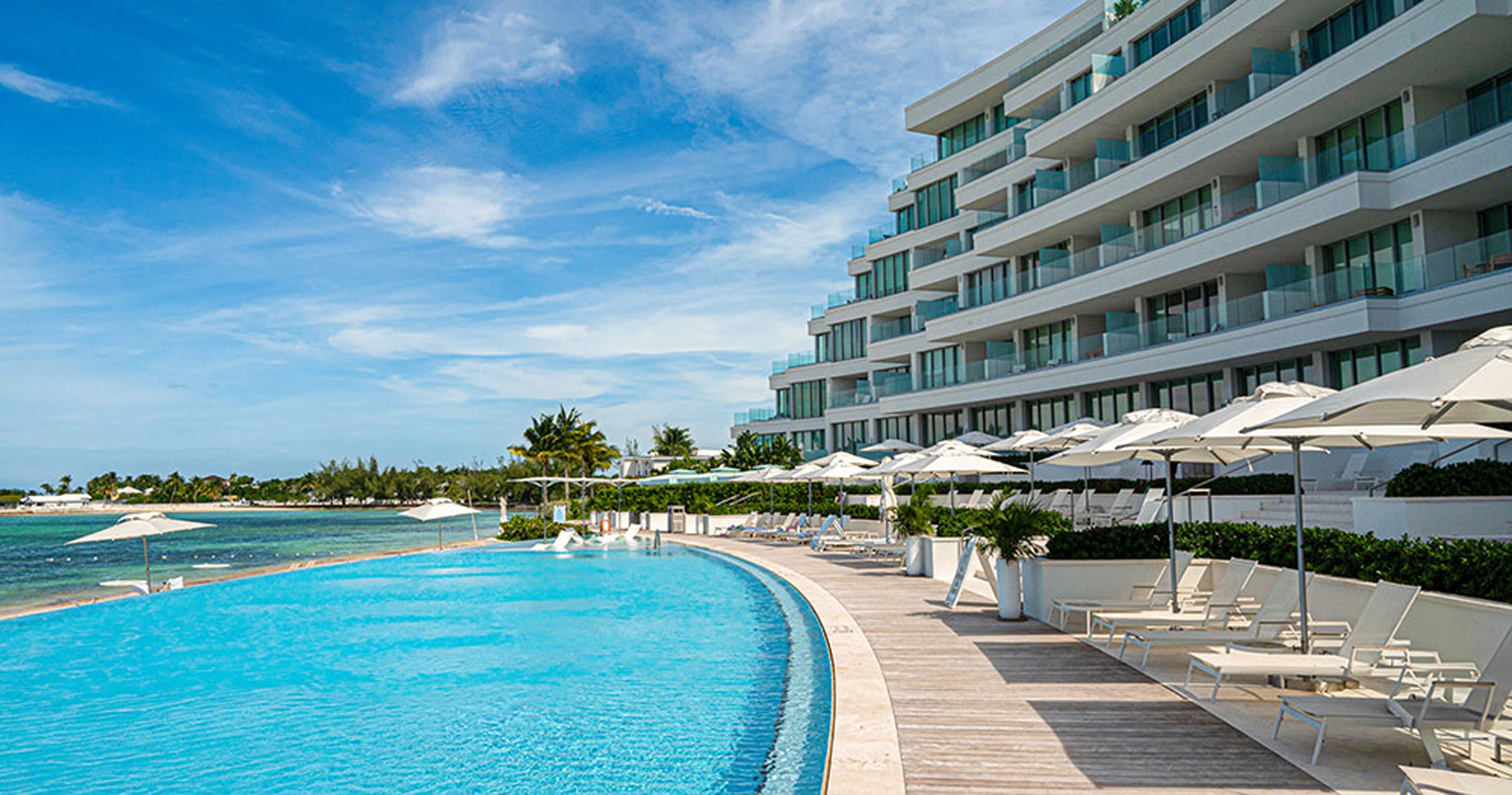 Luxury hotel pool area with clear blue water and white buildings.