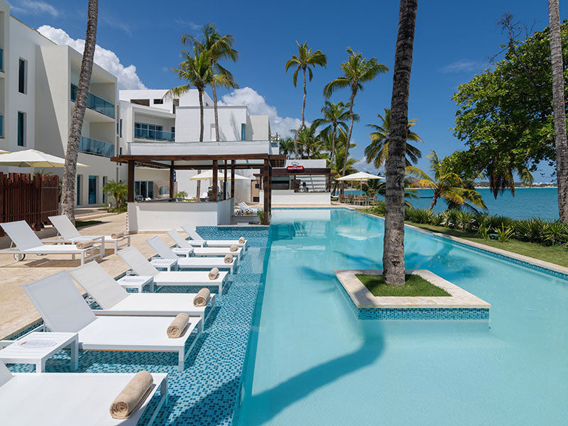 Pool with chairs, suites in the background with ocean view.