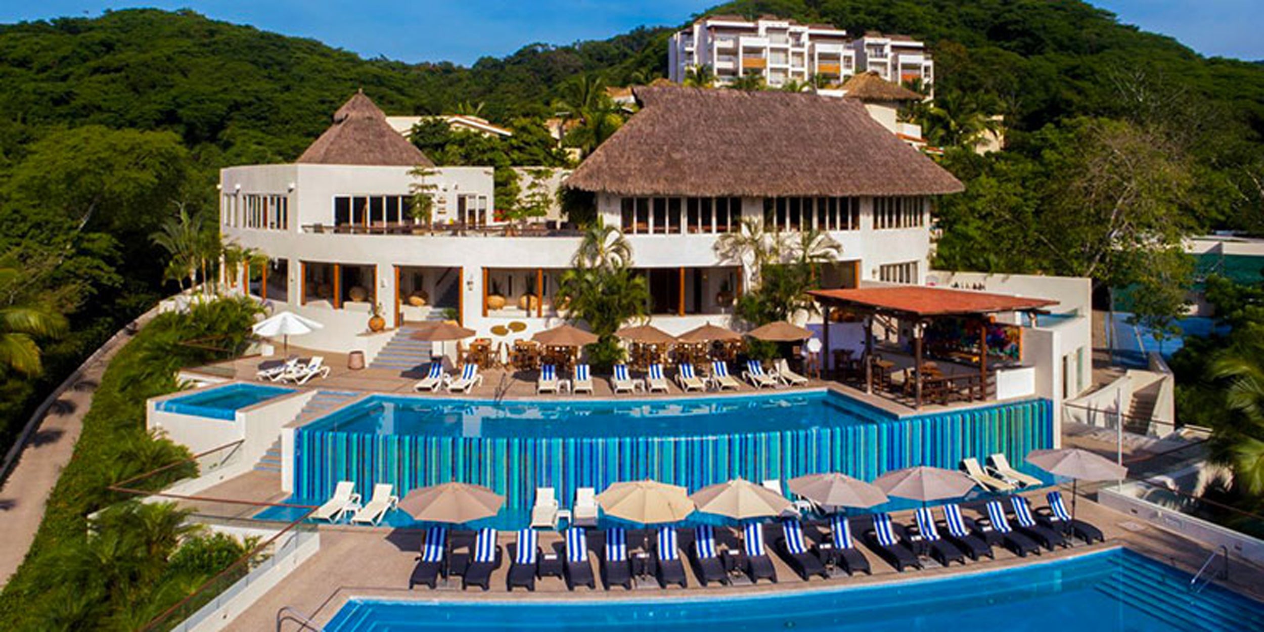 Luxury resort with multiple pools and cabanas surrounded by lush greenery.