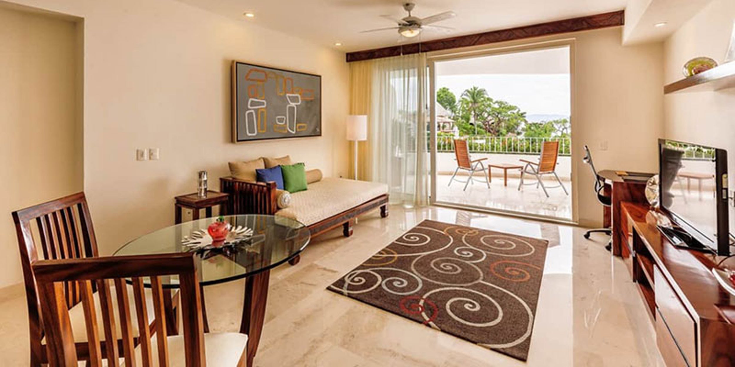 Living room with a couch, chairs, dining table, and a view of a garden.
