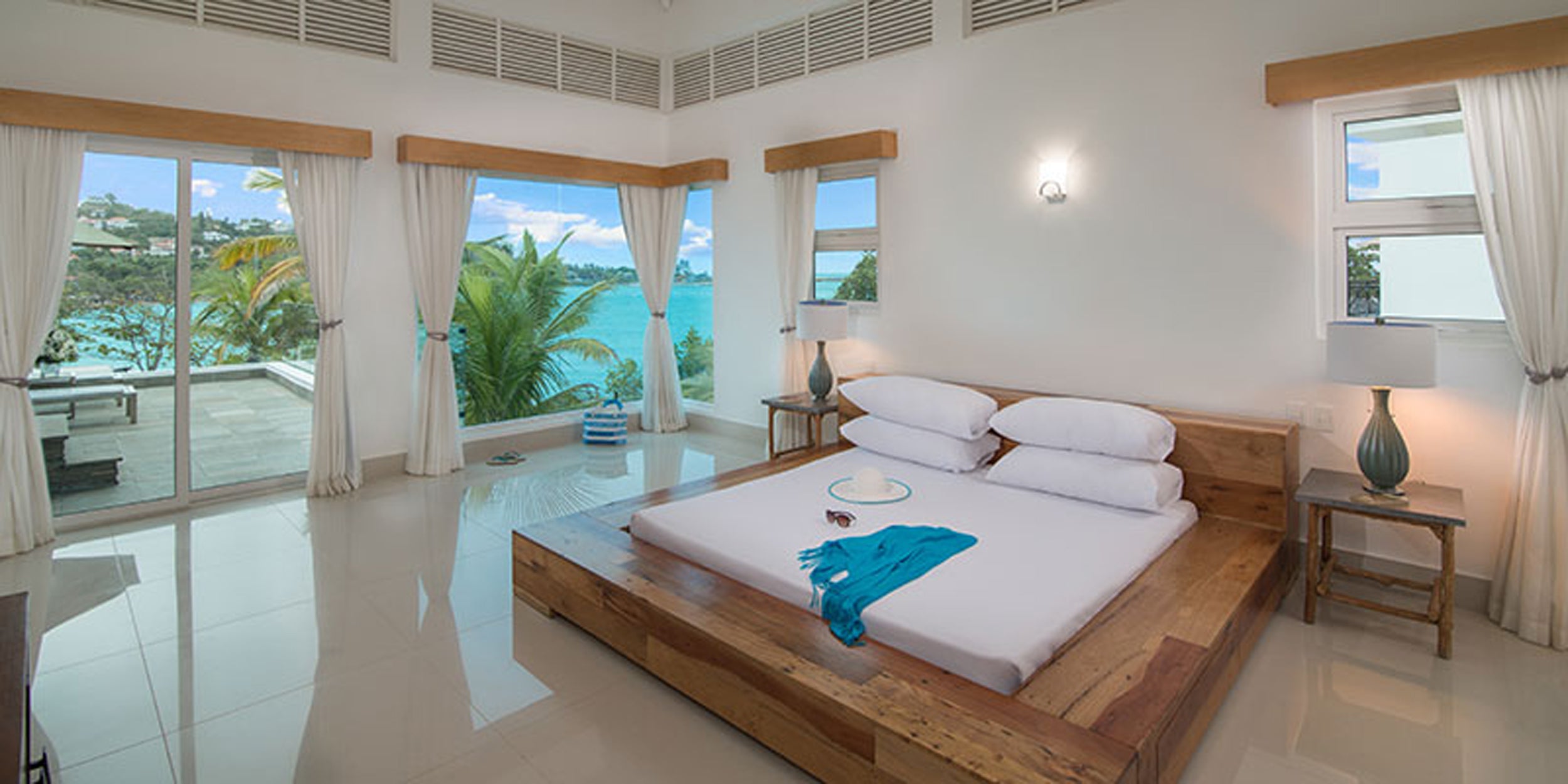 Modern bedroom with a large bed, windows, and outdoor view.