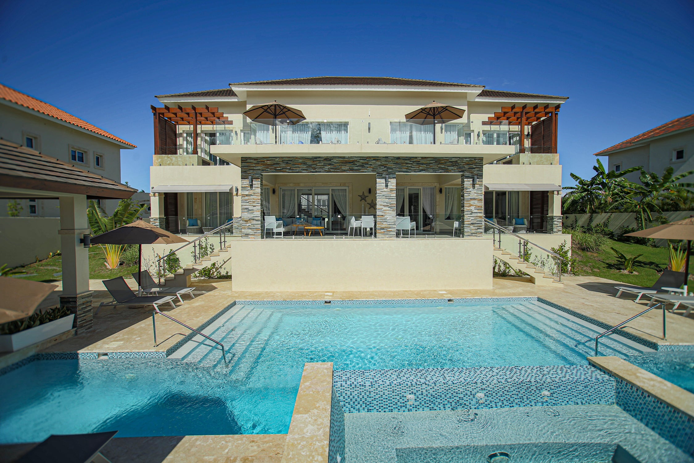Modern villa with a large pool area on a clear day