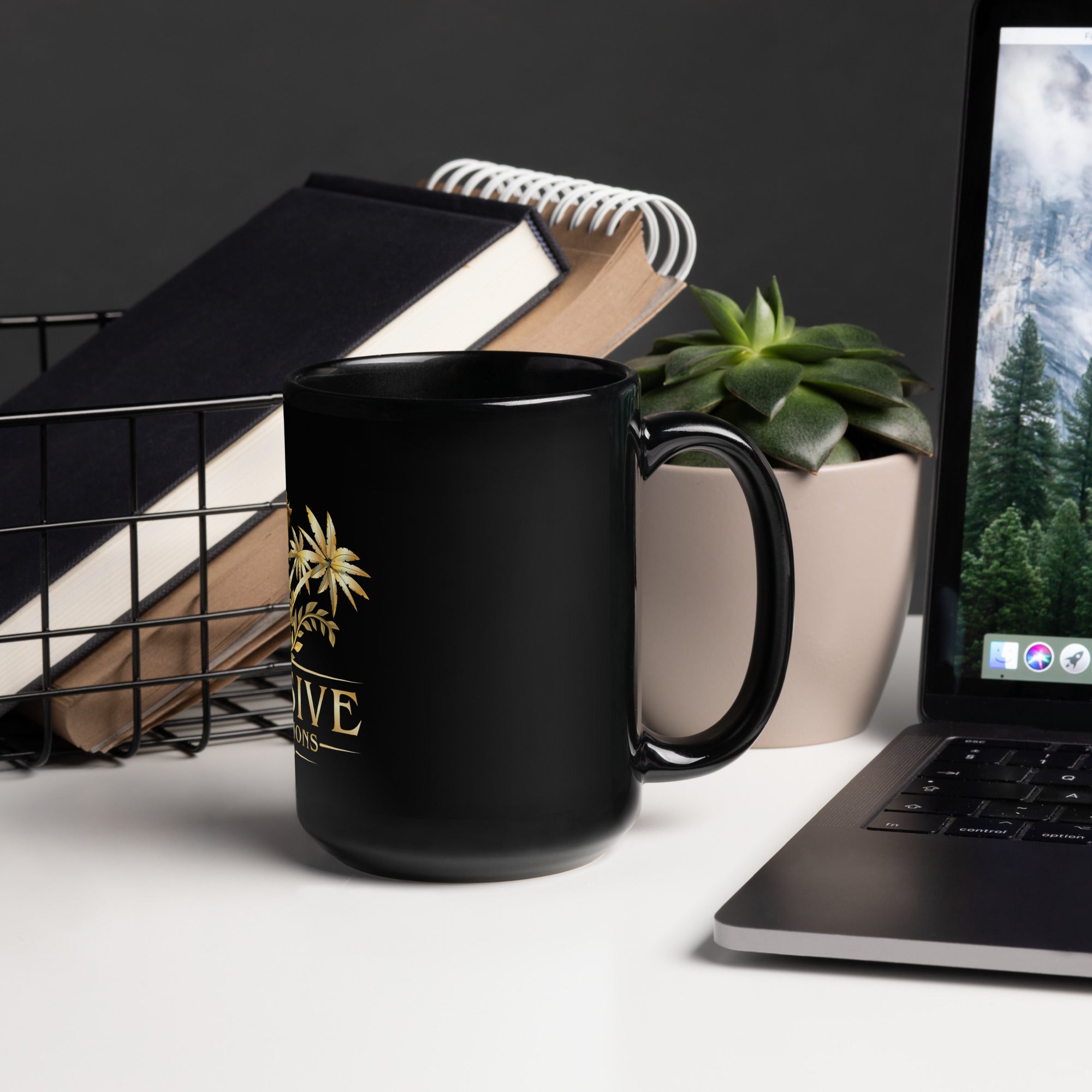 Black mug with a logo on a desk with a laptop and books in the background